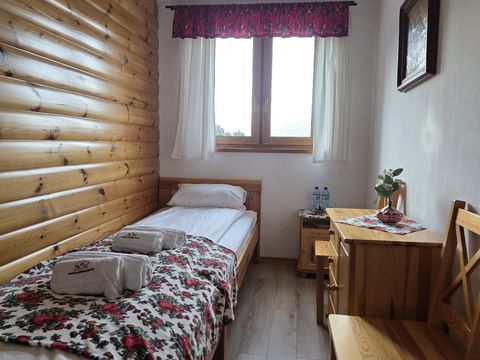 Apartament — pokój z łóżkiem pojedynczym, komodą i krzesłem przy oknie
