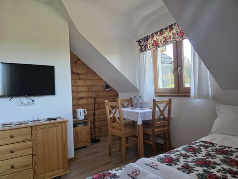 Apartament — stolik z krzesłami przy oknie, komoda i telewizor