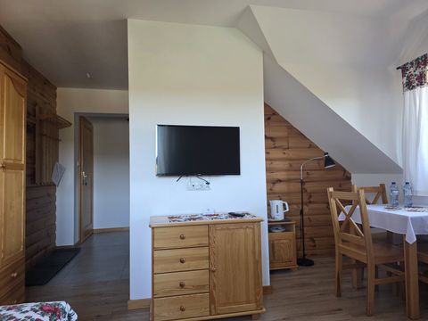 Apartament — telewizor na ścianie, komoda, czajnik i stolik