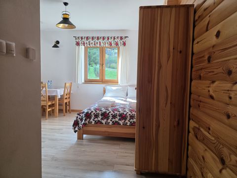 Pokój 1 widziany od wejścia — szafa, łóżko i stolik
